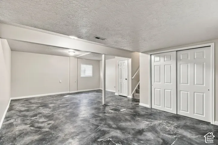 Expansive room featuring a unique floor finish, multiple doors, and a window for natural illumination