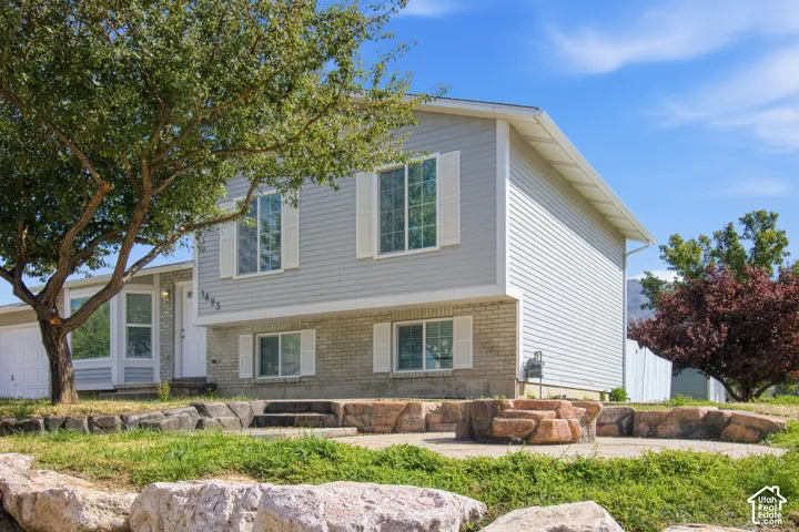 Two-story residence featuring light gray siding and a stone veneer foundation