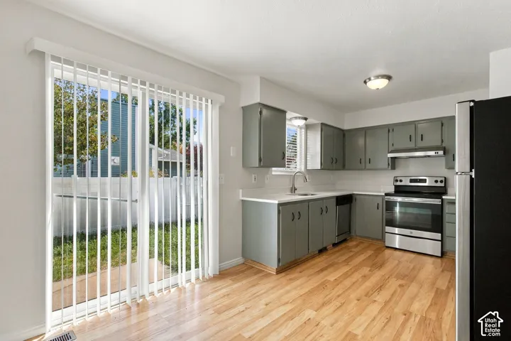 Kitchen featuring wood-finish flooring, gray cabinetry, white countertops, and stainless steel appliances