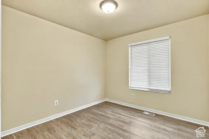 Neutral wall finish, wood-finish flooring, and a single window with blinds