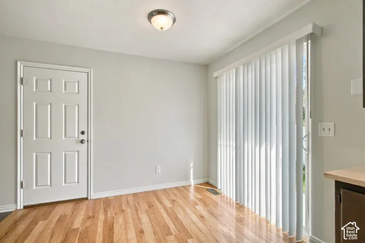 Wood-finish flooring, white paneled door, vertical blinds, and a built-in light fixture