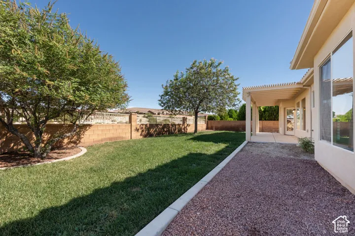 Expansive backyard featuring a covered patio, xeriscape landscaping, and a block fence