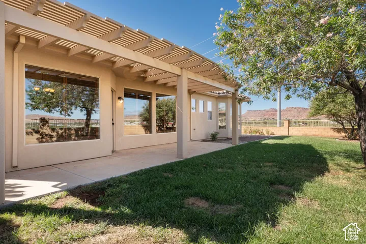 Expansive backyard featuring a concrete patio, a pergola, and green lawn