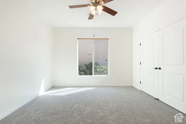 Neutral wall tones, gray carpet flooring, ceiling fan with integrated lighting, and white paneled doors with matte black hardware