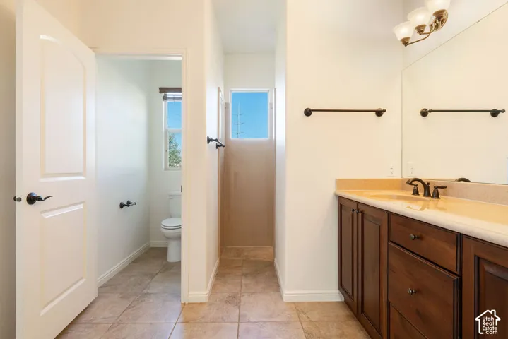 Bathroom featuring a wood-finish vanity with an integrated sink and countertop, a large wall-mounted mirror, and tile flooring