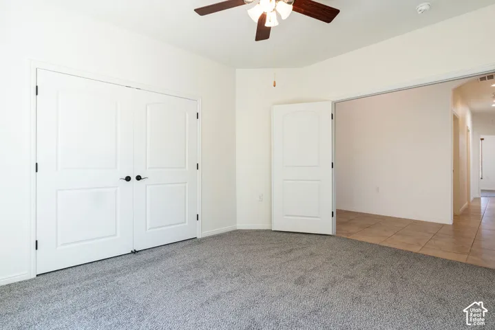 Soft gray carpeting, white walls, and a ceiling fan with integrated lighting