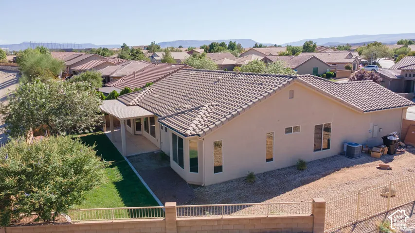 Tile roof, stucco exterior, covered patio, manicured lawn, and walled perimeter