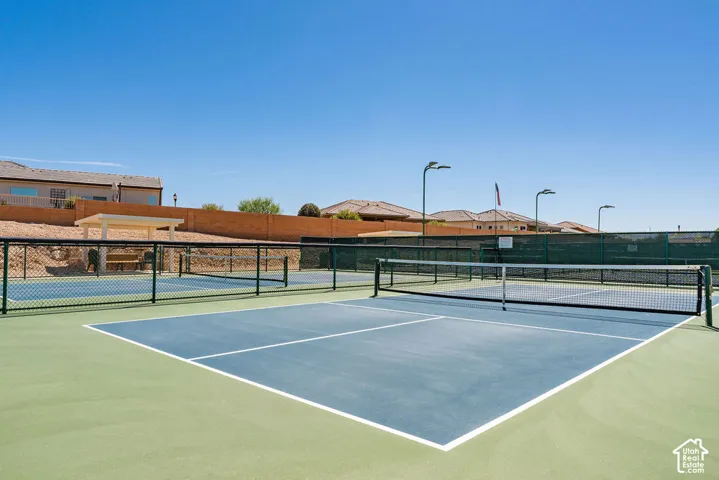 Hard-surface pickleball court with a net, perimeter fencing, and overhead lighting