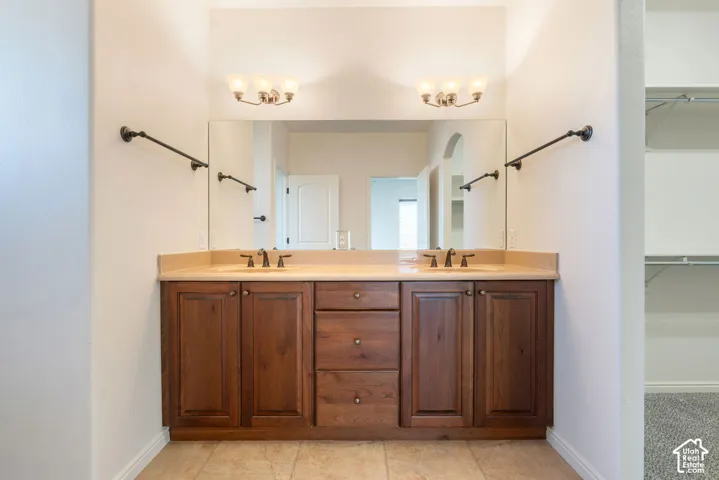 Dual vanity with integrated sinks, a stone-finish countertop, wood-finish cabinetry, and overhead sconce lighting