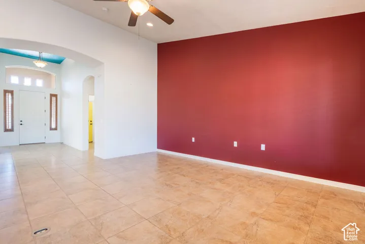 Tile flooring, vaulted ceiling, ceiling fan, white paneled door, arched doorway