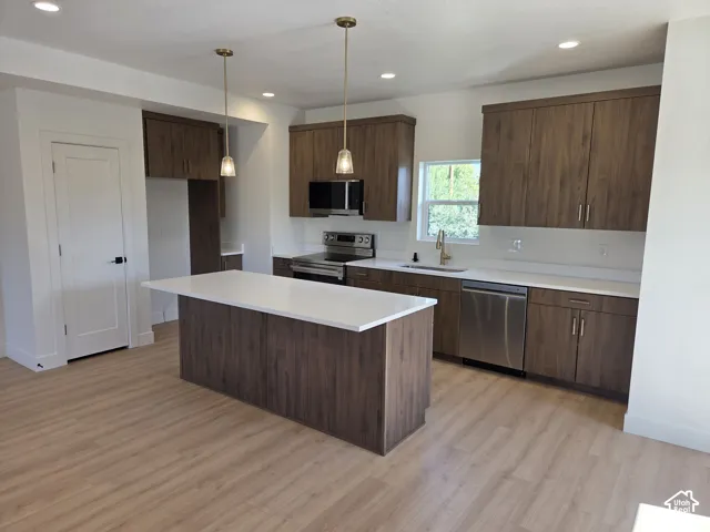 Kitchen featuring wood-finish cabinetry, white countertops, stainless steel appliances, and pendant lighting