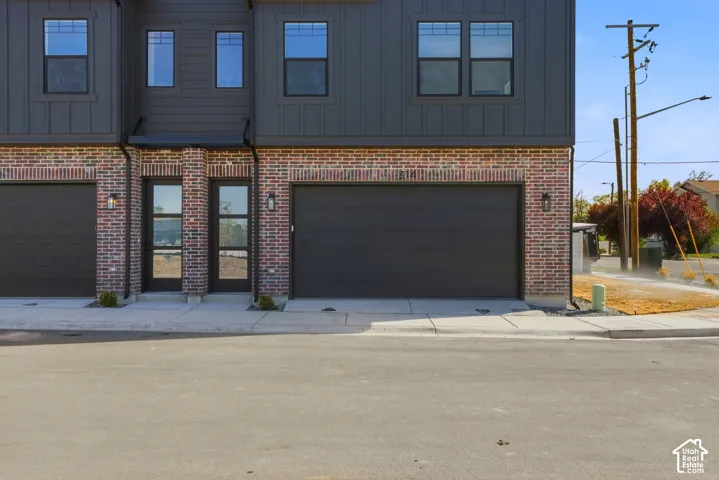 Brick facade with dark paneling, full-light entry doors, and integrated garage access