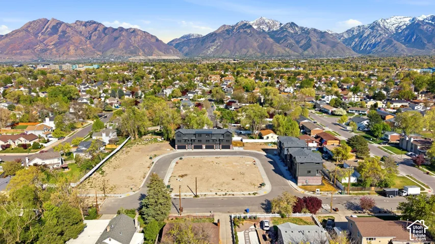 Mountain backdrop, established neighborhood, residential streets, undeveloped land parcels, modern multi-unit structures