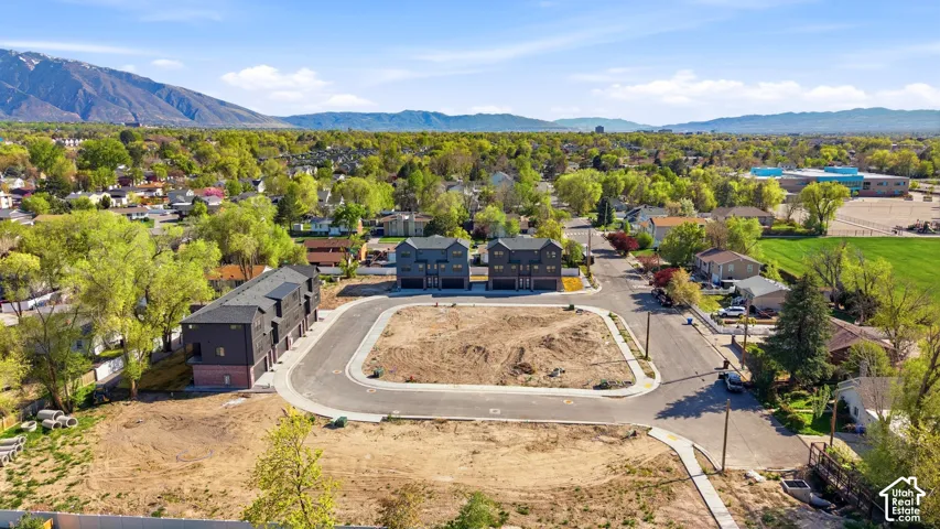 Newly developed residential area featuring multiple building lots, existing townhome structures, paved streets, and a mountainous backdrop