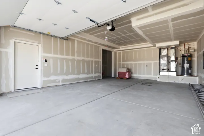 Unfinished garage space with concrete flooring, overhead garage door system, and utilities