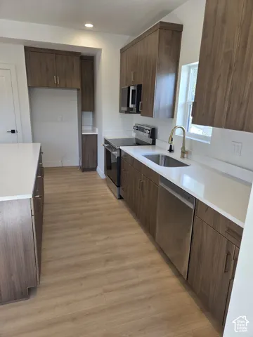 Contemporary kitchen featuring wood-finish cabinetry, white countertops, stainless steel appliances, and wood-finish flooring