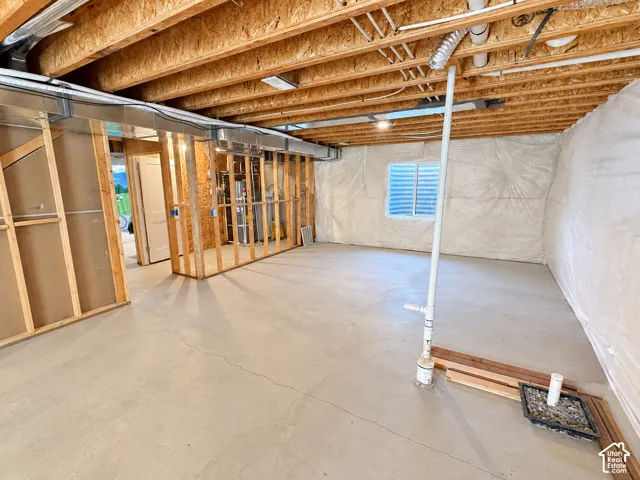 Unfinished basement with concrete flooring, exposed wood ceiling joists, and framed interior walls