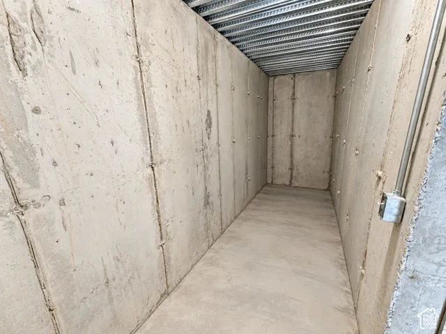 Concrete floor and walls with a metal deck ceiling, featuring exposed conduit and an electrical box