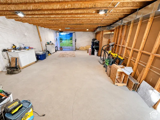 Unfinished basement featuring exposed wood joists, concrete flooring, and visible ductwork