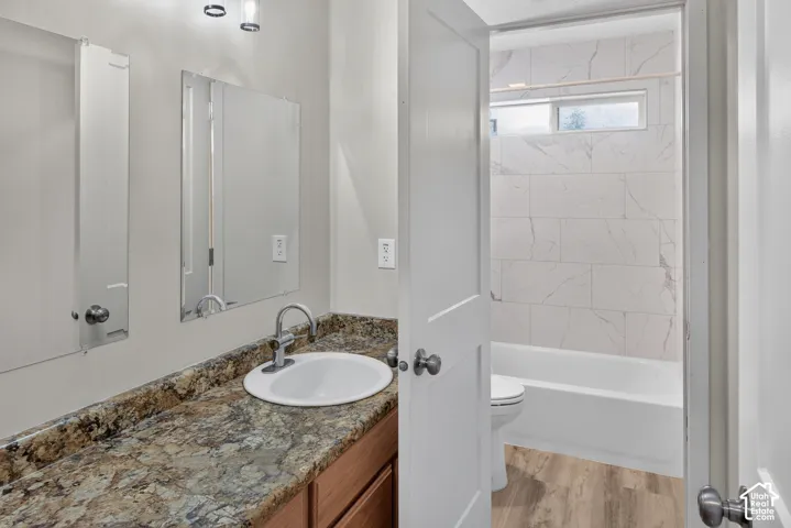 Bathroom featuring a vanity with a stone-finish countertop, undermount sink, and wood-finish cabinetry