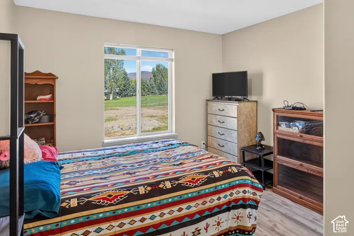 Large window, light neutral wall color, and wood-finish flooring