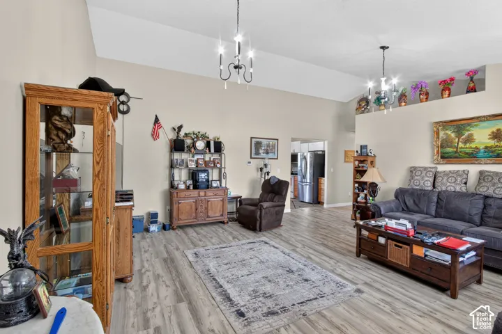Vaulted ceiling with decorative chandelier lighting, wood-finish flooring, and neutral wall tones