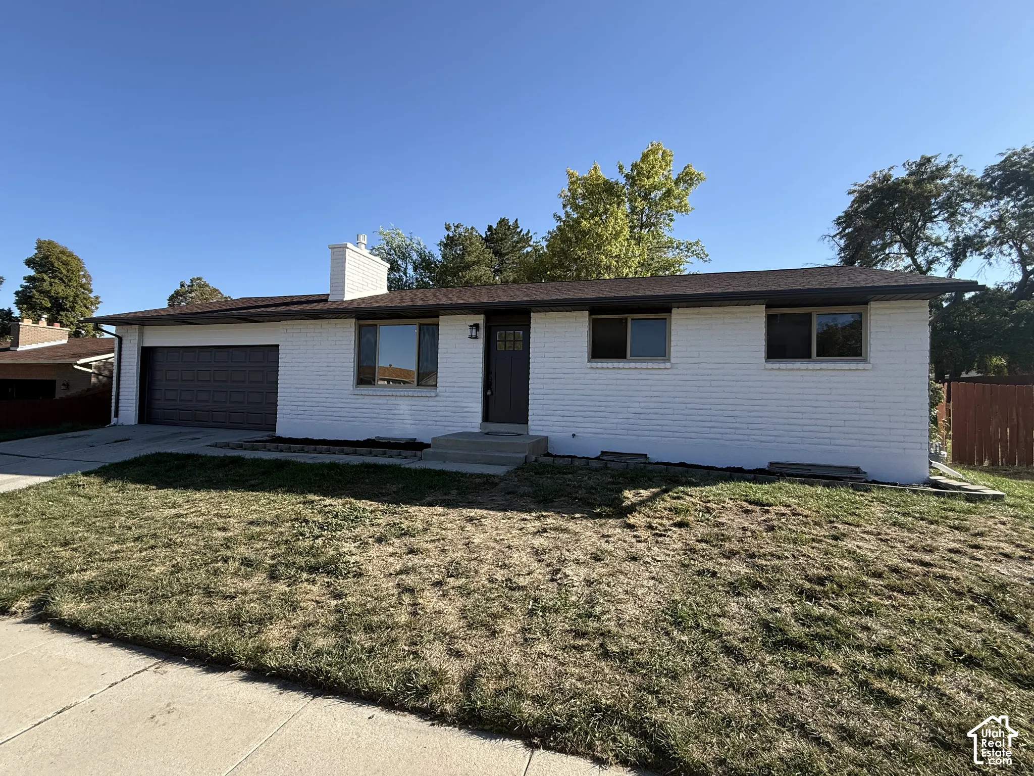White brick exterior with a dark brown garage door, dark brown front door, and a white chimney