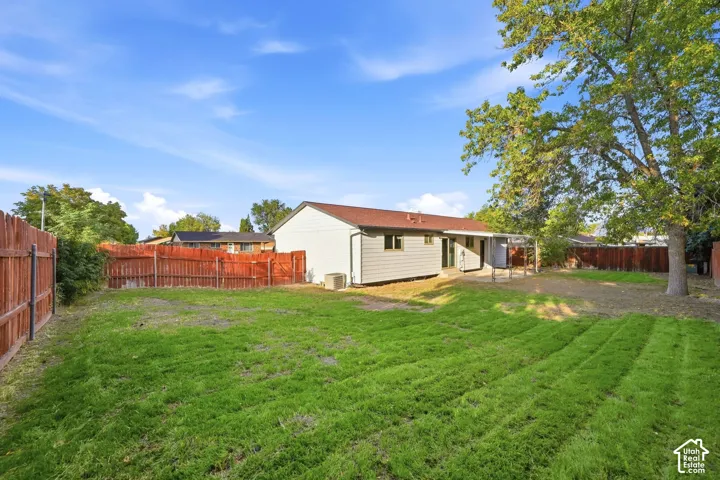 Expansive grass lawn, wooden privacy fencing, covered patio, and mature tree