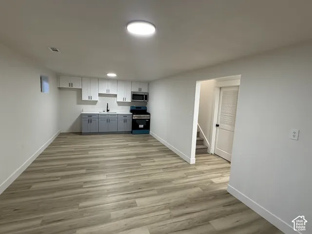 Basement kitchen with white upper cabinetry, gray lower cabinetry, and a stainless steel microwave