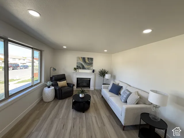 Recessed lighting, wood-finish flooring, white walls, and a fireplace with a white mantel