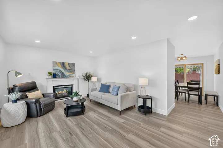 Light wood-finish flooring throughout, recessed lighting, and a white mantel over a built-in fireplace