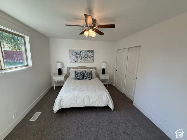Recessed window with white trim, dark textured carpeting, and a ceiling fan with integrated lighting