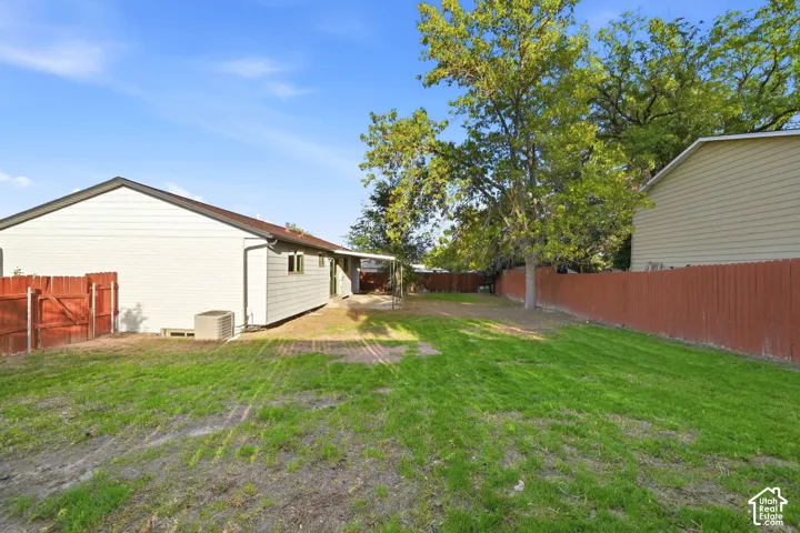 Expansive backyard featuring a manicured lawn, established trees, and a full privacy fence