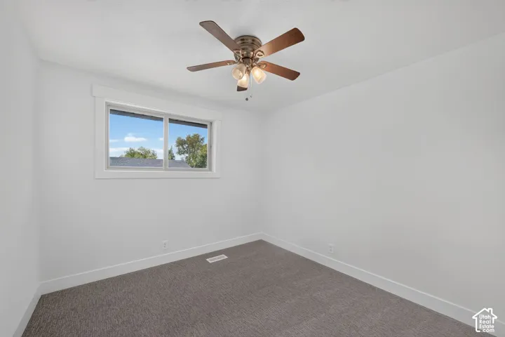 Window with white trim, ceiling fan with light fixture, light gray carpeting, and white walls