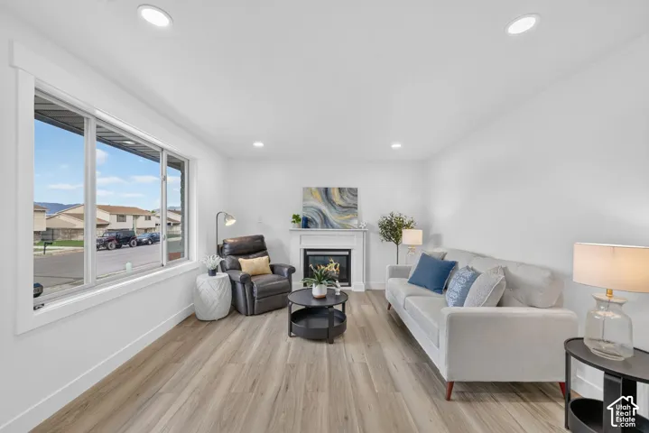 Recessed lighting throughout, wood-finish flooring, and a fireplace with a white mantel