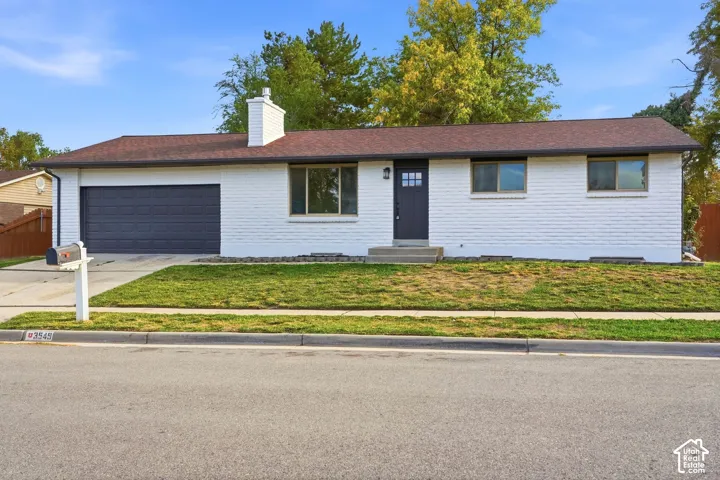 Single-story residence featuring white brick exterior, dark gray garage door, and a matching front entry door