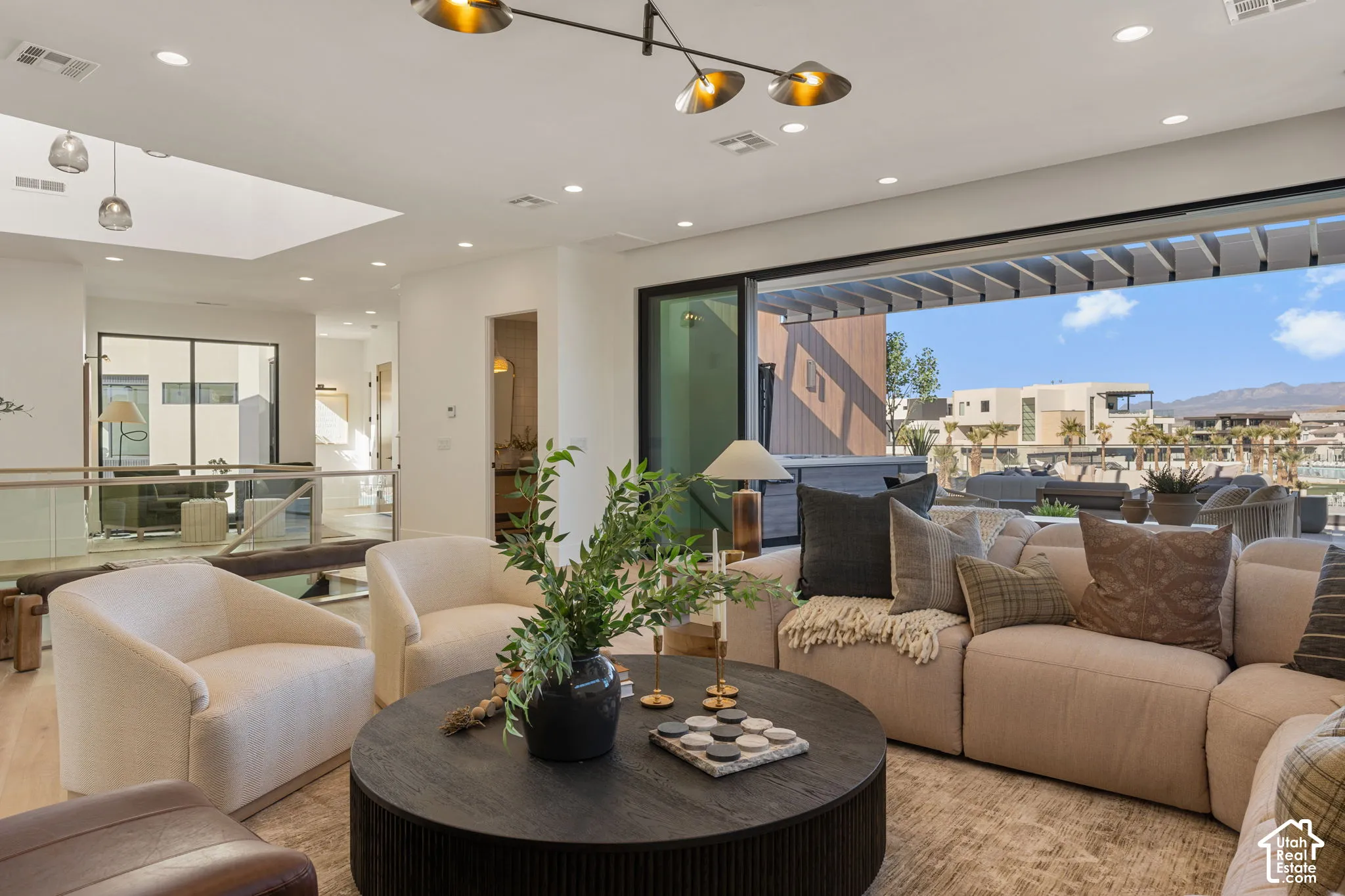 Open-concept living space with a large sliding glass door, a modern linear chandelier, recessed lighting, and a skylight