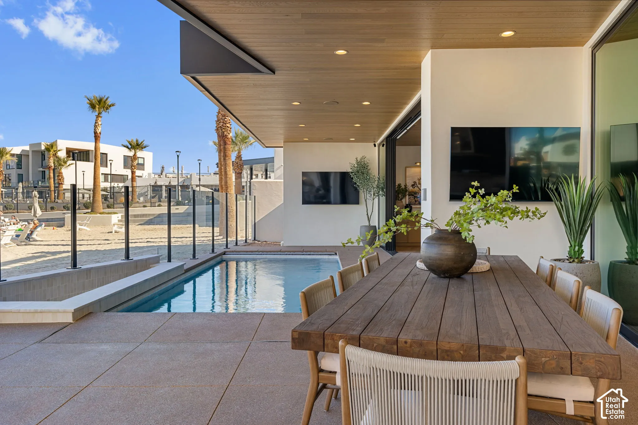 Outdoor living space with a swimming pool, glass panel fencing, and a built-in outdoor dining area