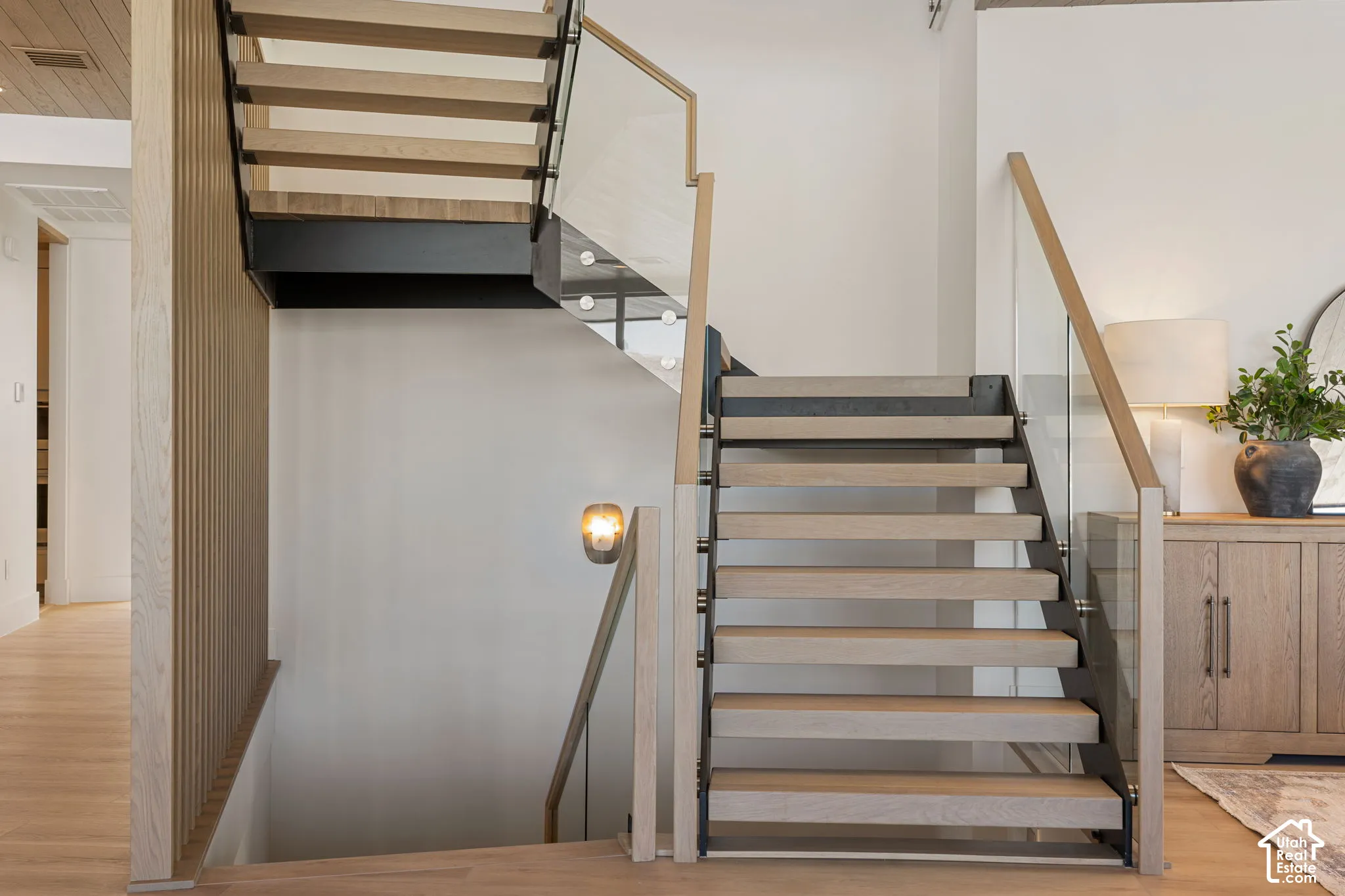 Floating staircase with wood-finish treads, glass railing, and wood-finish handrails