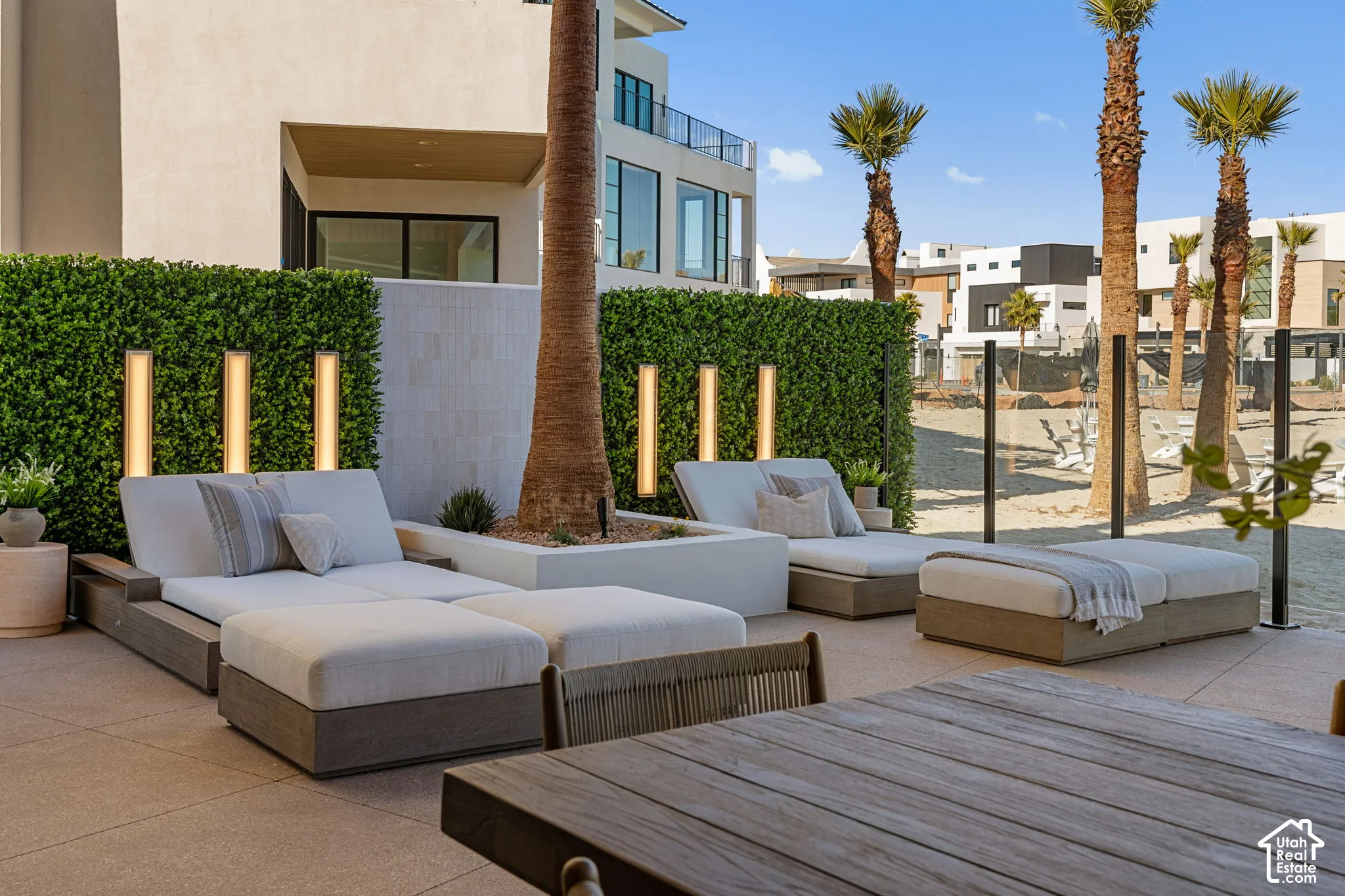Expansive outdoor patio with large format tile, integrated lighting within a privacy hedge, and a built-in planter