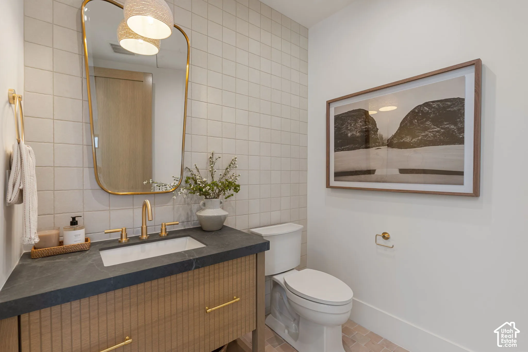 Vanity with fluted wood-finish cabinetry, dark countertop, and gold-finish fixtures