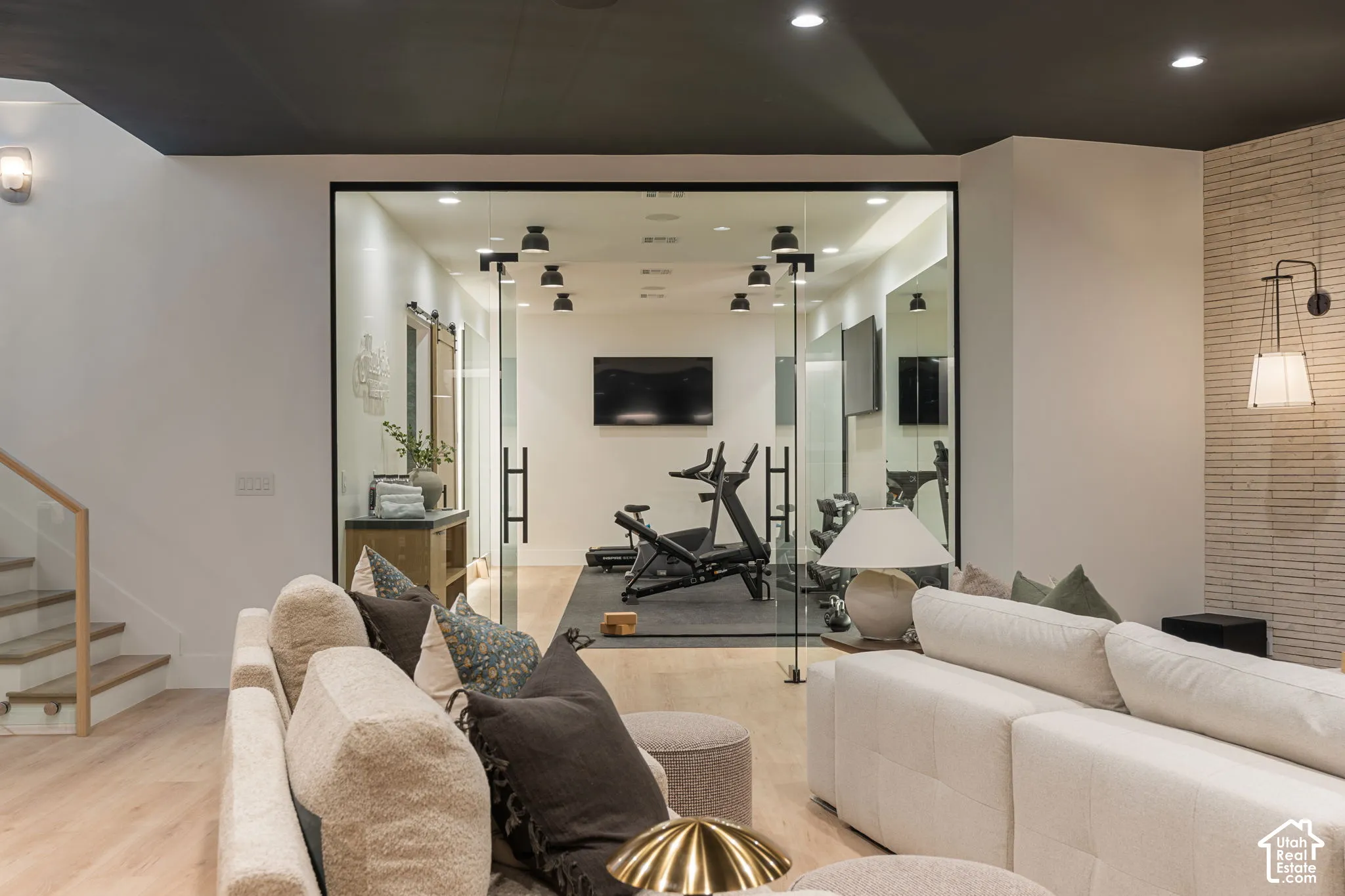 Glass-enclosed room with track lighting, light wood-finish flooring, and black trim