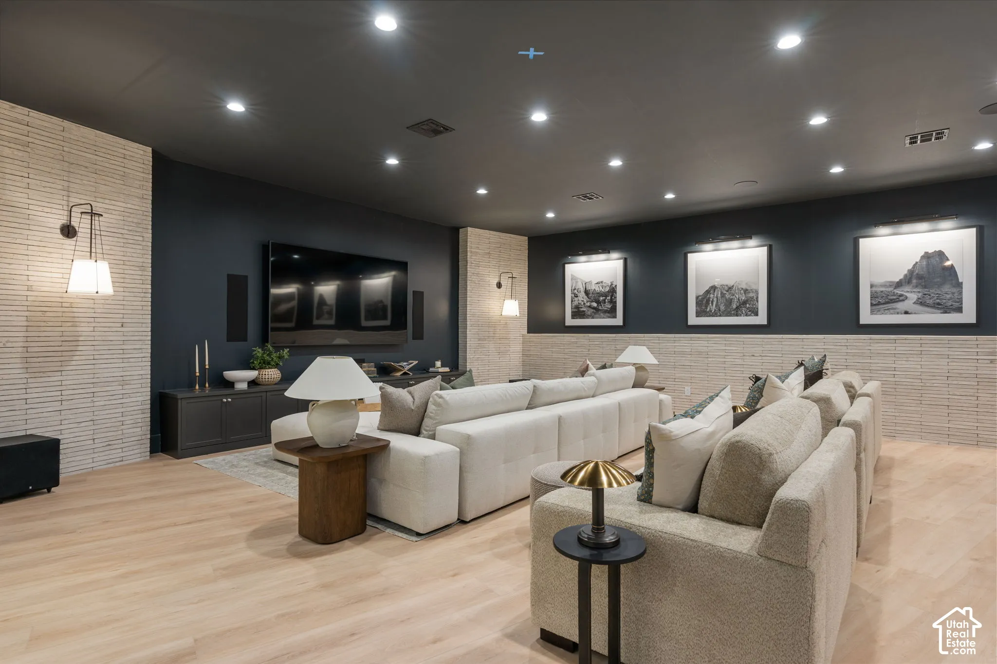Recessed ceiling lighting, wood-finish flooring, two-tone wall treatment, built-in media console, and wall-mounted sconces