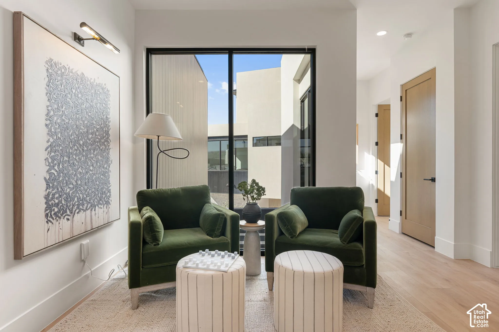 Expansive floor-to-ceiling windows, light wood-finish flooring, recessed lighting, and solid core doors with matte black hardware