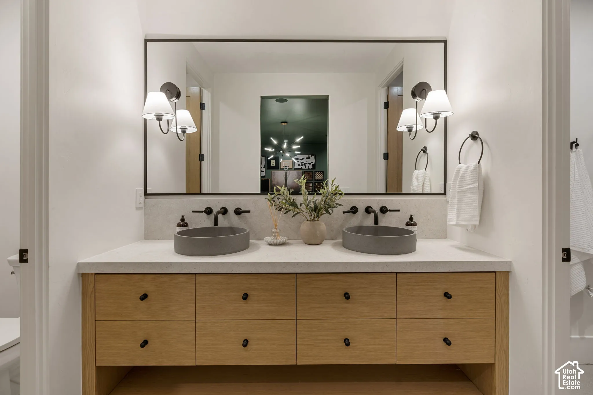 Dual vessel sinks with wall-mounted matte black faucets, set within a light-toned countertop