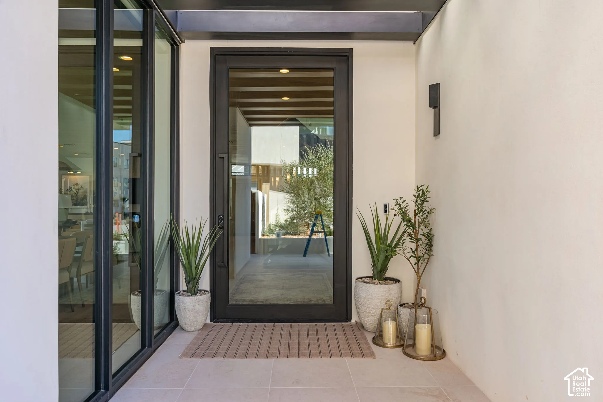 Recessed entry with a full-light entry door, adjacent full-light sidelight, exterior wall sconce, and tiled flooring