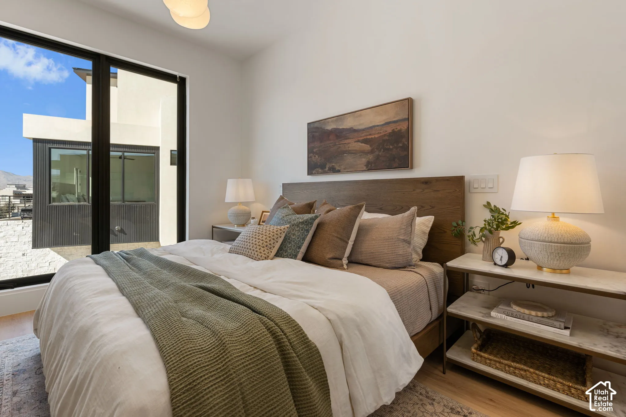 Wood-finish flooring, full-height windows, and a wood-finish headboard create a refined ambiance