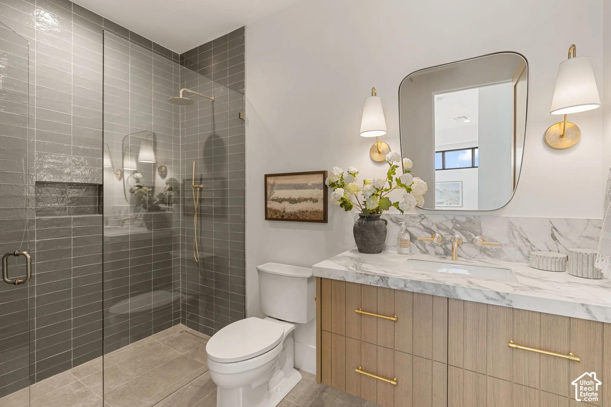 Glass-enclosed shower with gray subway tile, built-in shower niche, and gold-finish fixtures