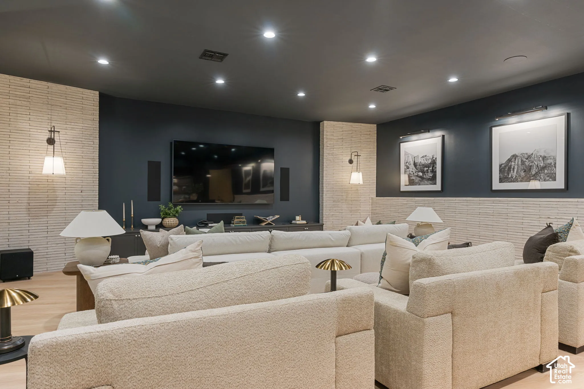 Recessed ceiling lighting, wood-finish flooring, accent wall with linear brick pattern, built-in display console, and wall-mounted sconces