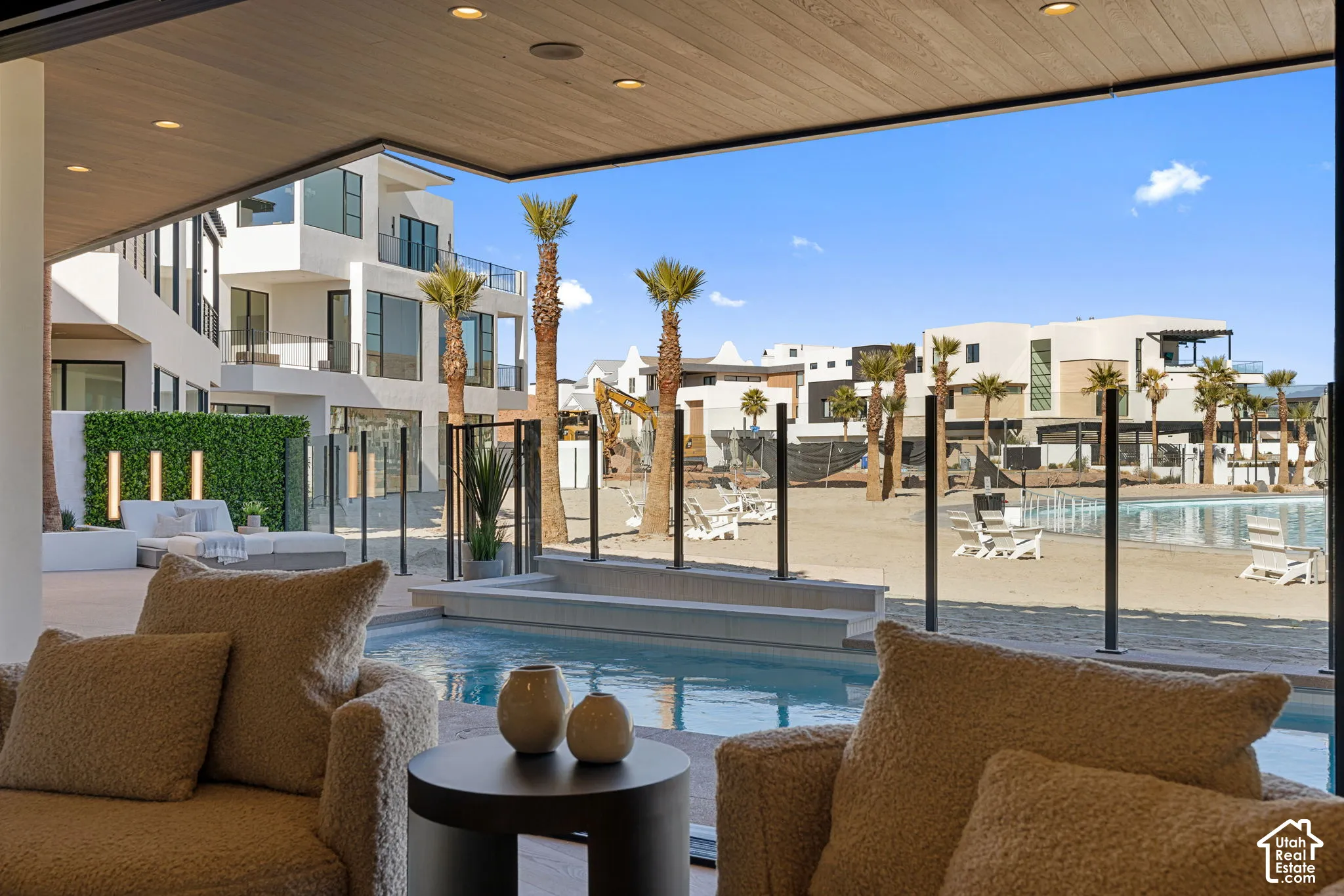 Outdoor living area featuring a built-in pool, adjacent patio, and direct access to a sandy area with a water feature